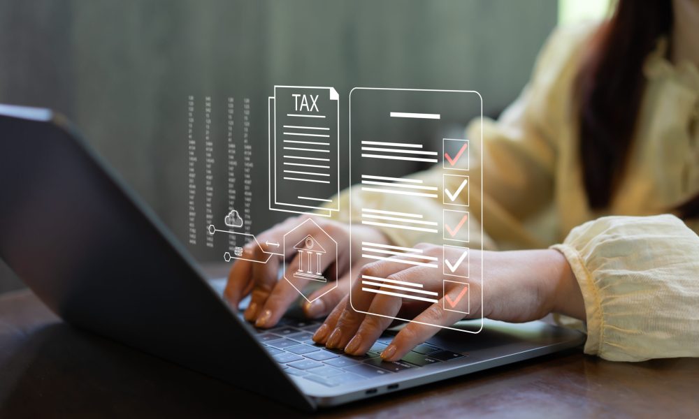 Businesswoman filing taxes online using a laptop with digital tax form interface. E-filing, tax compliance, financial documentation, online accounting, fintech services and paperless workflow.
