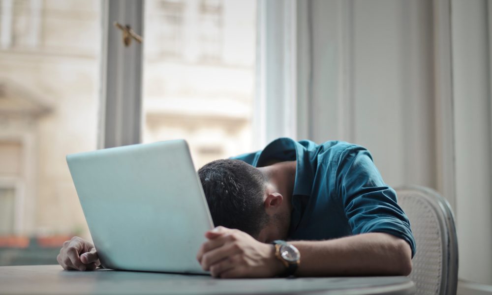 depressed man with head leaning on computer