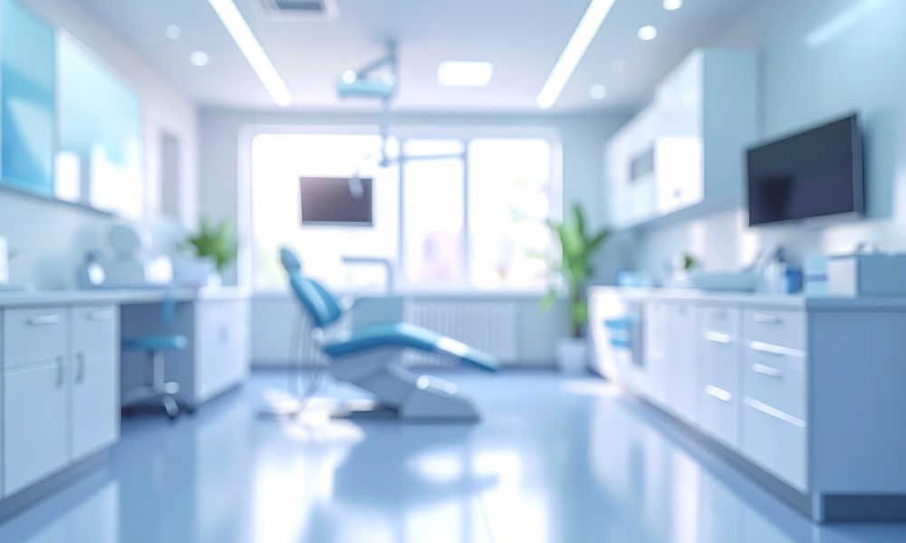 A blurry image presents a bright dental office interior with a chair, cabinets, and a window. The color palette is primarily blue and white