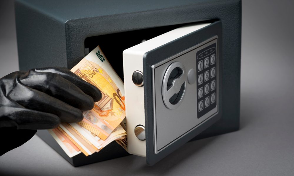Thief hand with money banknotes during safe code breaking.  Hacking safe
