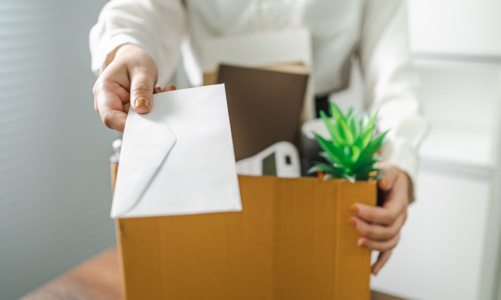 Business woman sending resignation letter and packing Stuff Resign Depress or carrying business cardboard box by desk in office. Change of job or fired from company.