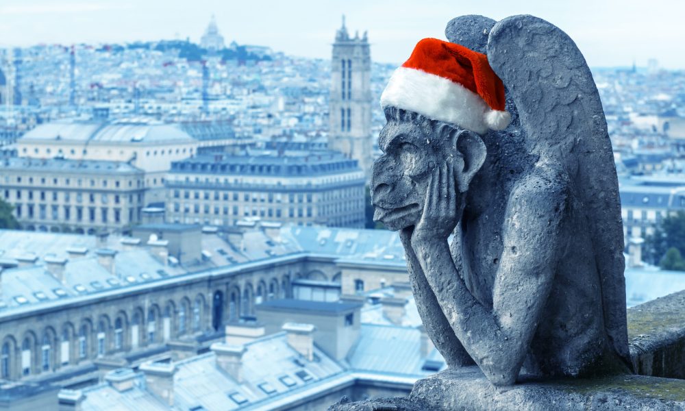 Christmas, New Year and fun concept, gargoyle (chimera) of Notre Dame de Paris cathedral with Santa hat, Paris, France. This place is landmark of Paris. Famous gothic statue in festive decoration.