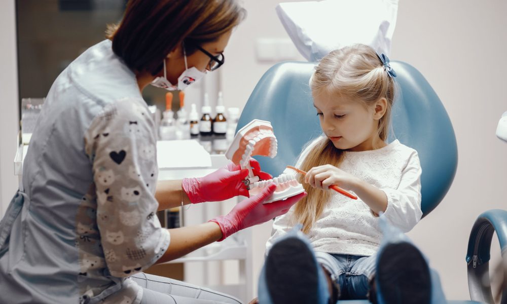 Little girl talking to the dendist. Child in the dentist's office. Woman in a uniform